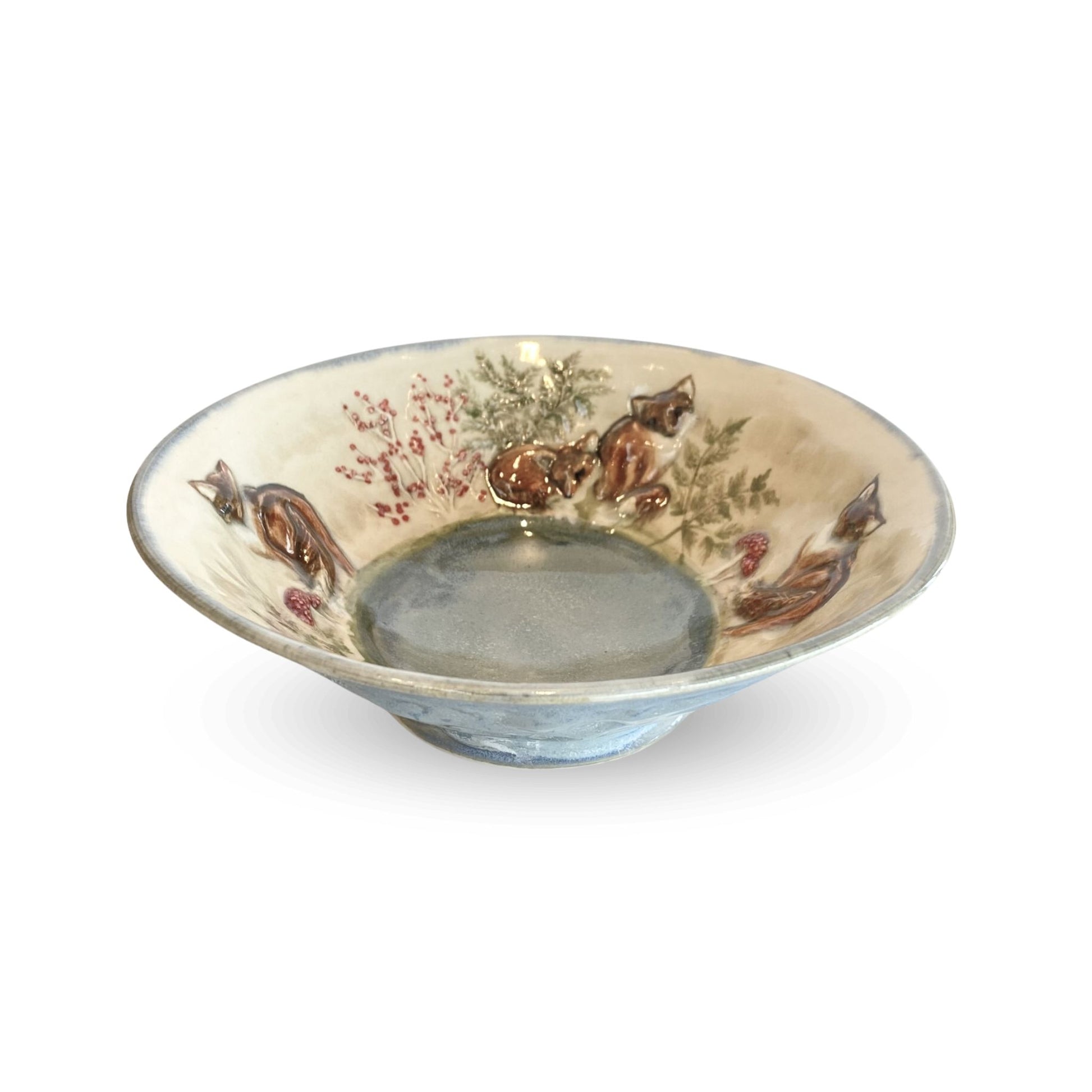 small blue decorative bowl with brown foxes and red berries and mushrooms